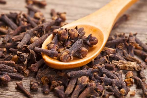 Cuillère en bois remplie de clous de girofle secs.