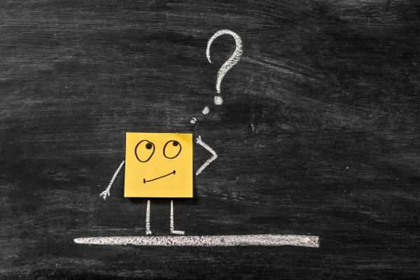 Dessin sur tableau noir d’un personnage en post-it jaune avec un point d’interrogation.