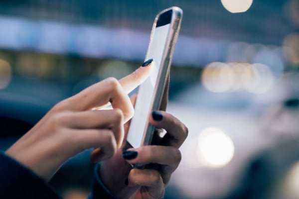 Utilisateur tapant sur un écran de téléphone en ville.