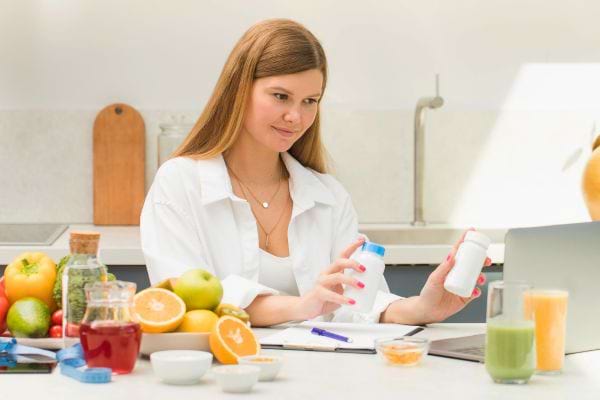 Femme nutritionniste analysant des produits à côté de fruits et jus.