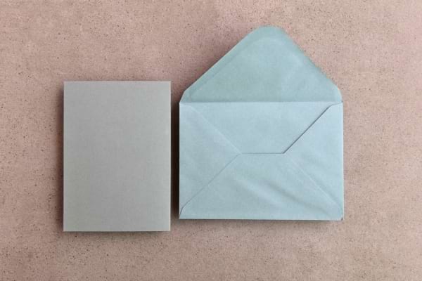 Enveloppe grise ouverte avec feuille.