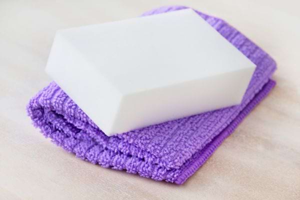 Éponge magique blanche posée sur un chiffon violet.