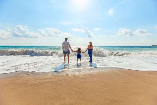 Famille tenant les mains face aux vagues.