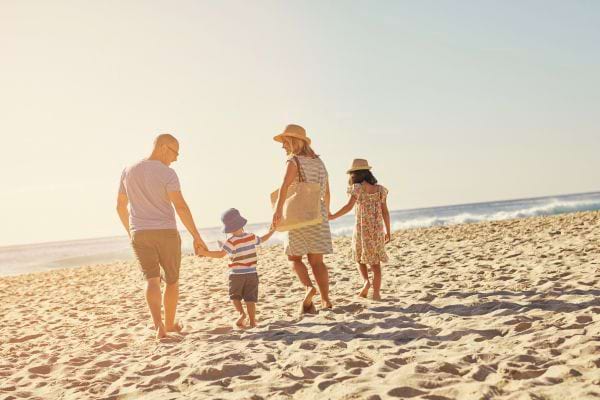 Famille marchant sur une plage ensoleillée.