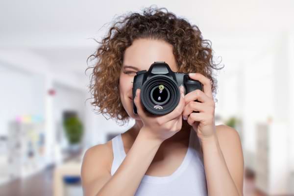Une femme tient un appareil photo et s’apprête à capturer un moment avec le sourire.