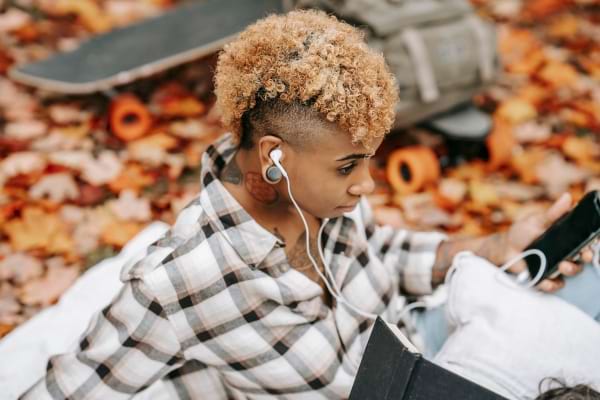 Jeune femme avec des écouteurs, utilisant son téléphone en extérieur.