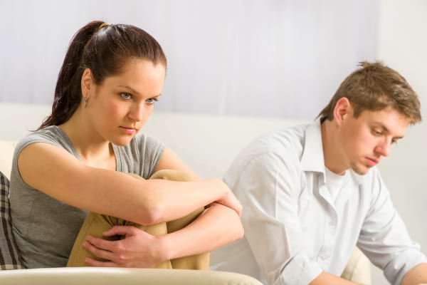 Une femme en colère regarde ailleurs, l’homme semble préoccupé, assis à côté d’elle.