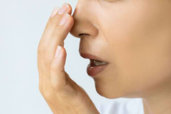 Une personne couvre sa bouche avec la main en raison d’une mauvaise haleine.