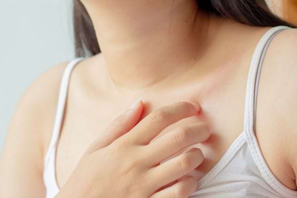 Une femme gratte sa poitrine à cause de démangeaisons cutanées.