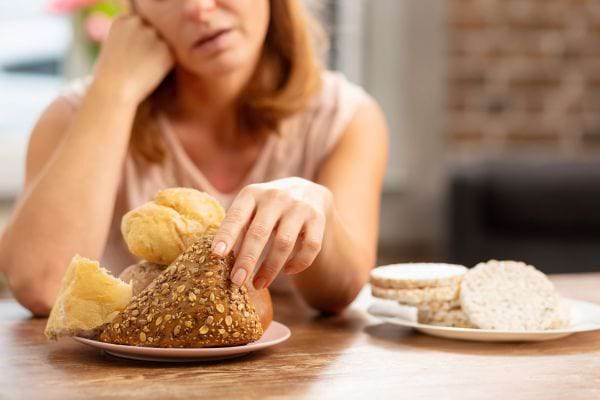 Une femme regarde des morceaux de pain posés sur une assiette.