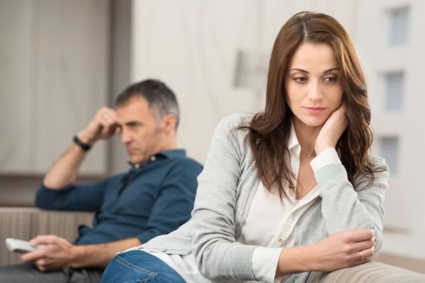 Une femme pensive regarde au loin, l’homme derrière elle semble absorbé par ses pensées