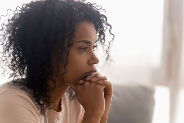 Une femme pensive appuie son menton sur ses mains.