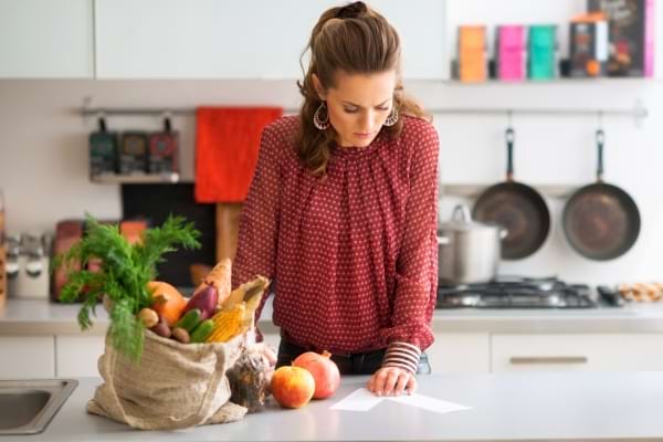 une femme range ses courses dans la cuisine