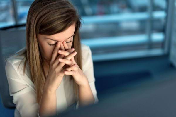 Une femme stressée se tient la tête avec inquiétude.