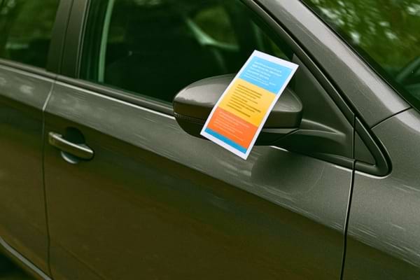 Flyer coloré coincé dans un rétroviseur de voiture.