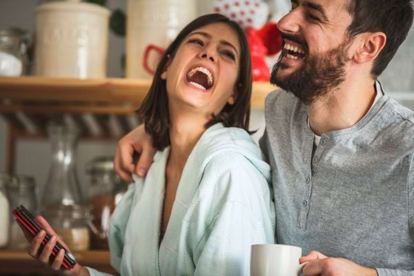 Un couple complice éclate de rire dans la cuisine.