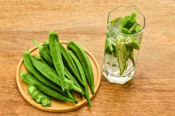 Des gombos frais posés sur une assiette et dans un verre d’eau.