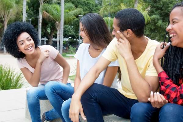 Groupe d’amis assis dehors en train de rire.