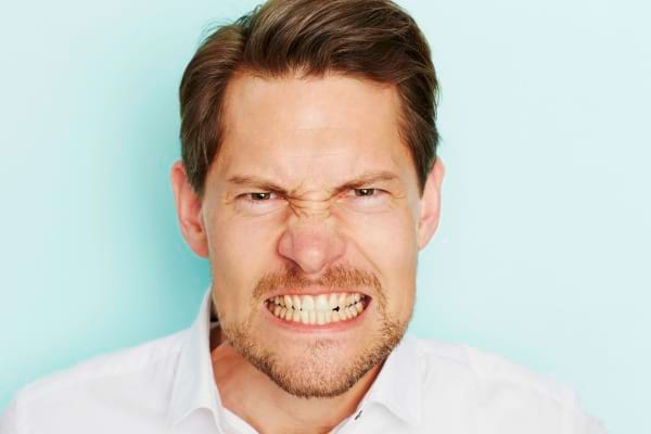 Homme exprimant la colère en grimaçant.