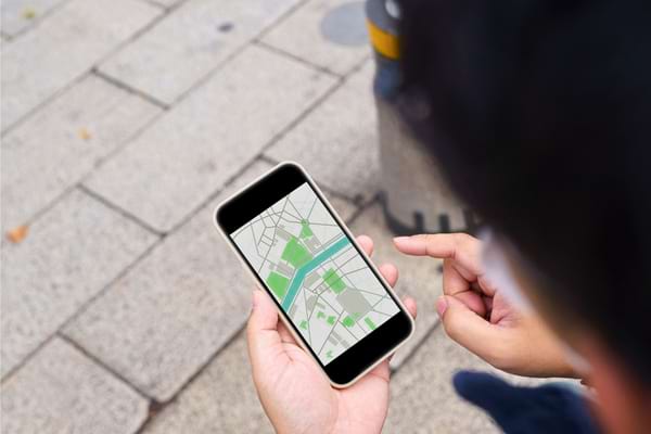 Homme consultant une carte sur son téléphone en extérieur.