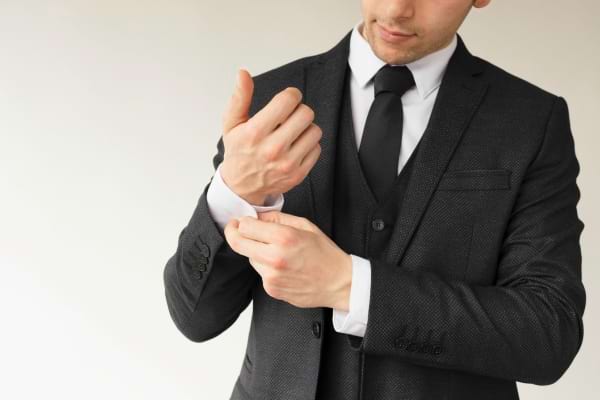 Homme en costume ajustant sa manche.