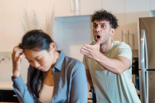 Un homme crie sur une femme qui détourne la tête, manifestement blessée et abattue.