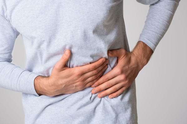 Un homme appuie sur son ventre douloureux avec ses mains.