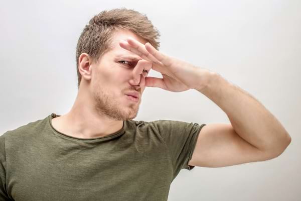 Homme se bouchant le nez avec la main.
