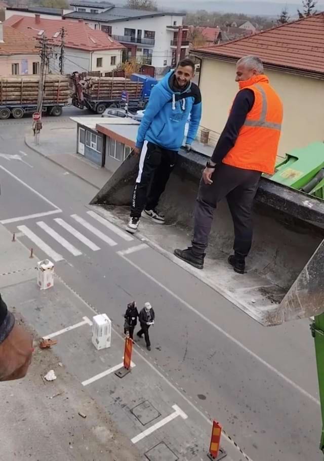 Deux hommes sur une pelle suspendue en hauteur.