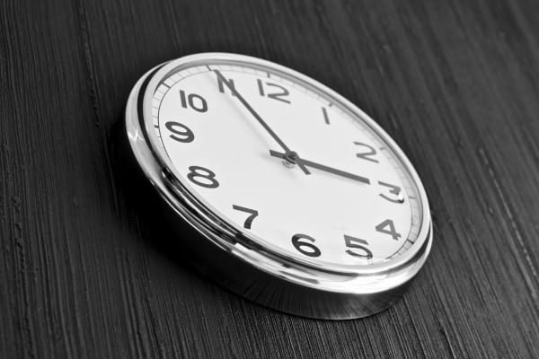 Une horloge murale indique l’heure sur un mur sombre.