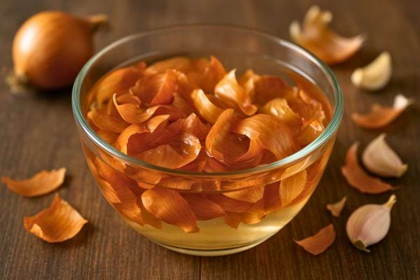 Des pelures d’oignon trempent dans un bol d’eau pour infusion naturelle.