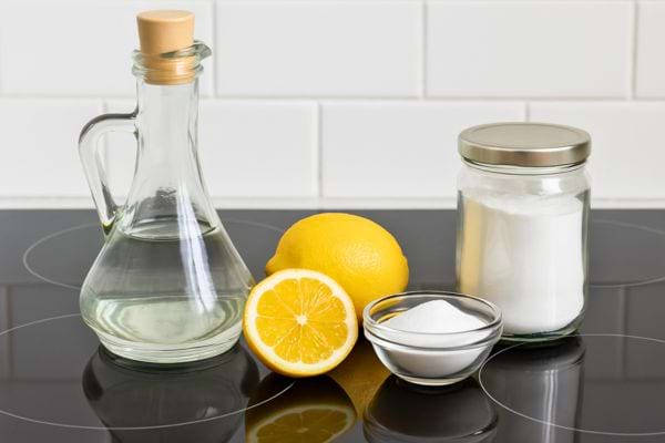 Bocal de bicarbonate, vinaigre et citrons posés sur une plaque.