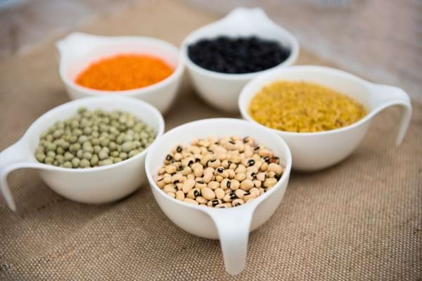 Cinq tasses blanches exposent différentes sortes de légumineuses sèches.