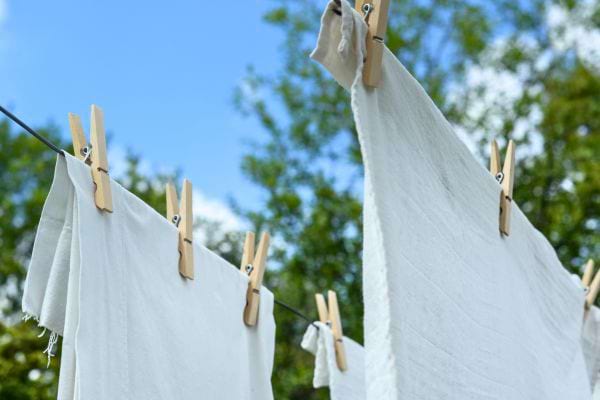 Draps blancs accrochés avec des pinces à linge sur un fil extérieur.