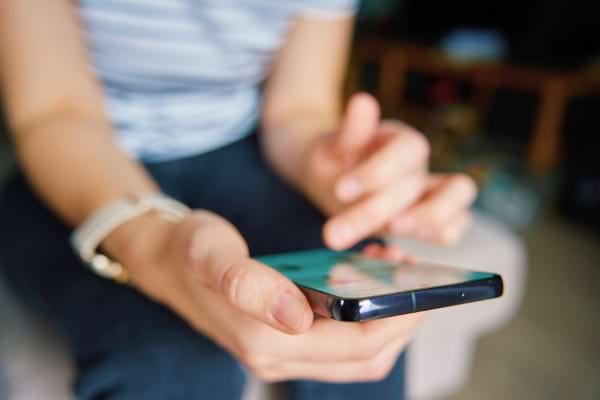 Une personne utilise un smartphone avec les deux mains.