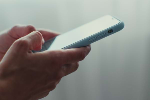 Gros plan d’une main tenant un téléphone blanc.