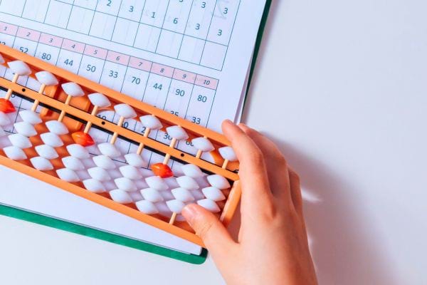 Une main d’enfant déplace les boules d’un abacus pour calculer.