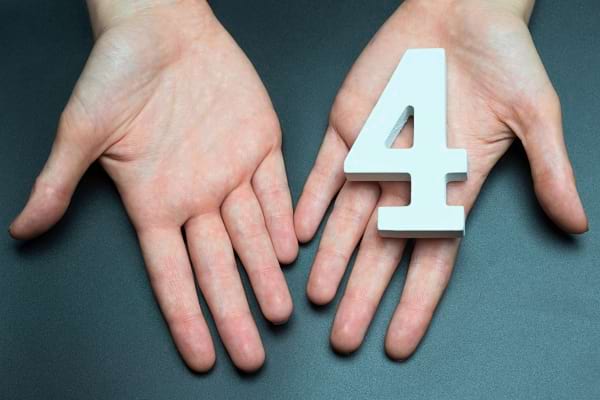 Deux mains tenant le chiffre quatre blanc.