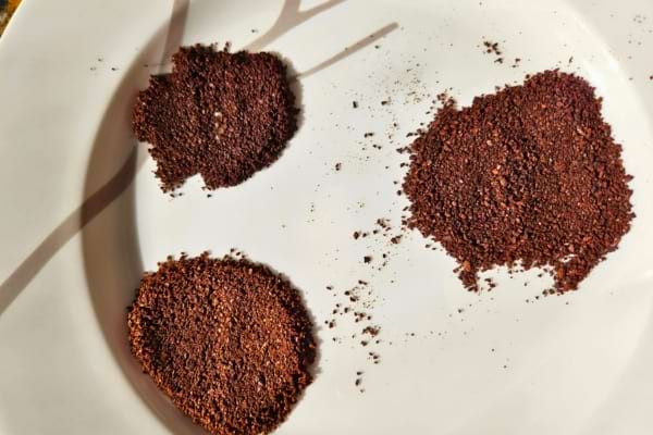 Trois tas de marc de café sur une assiette blanche.