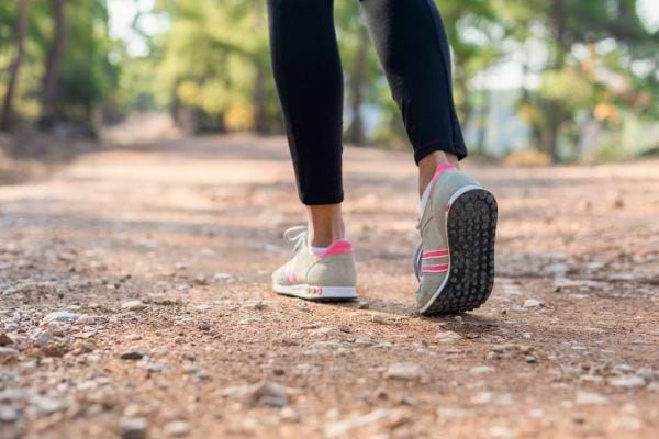 Une personne marche sur un chemin de terre avec des baskets.