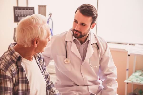Un médecin discute avec un patient âgé dans un cabinet.