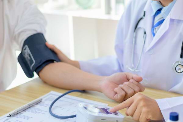 Un médecin prend la tension d’un patient avec un tensiomètre électronique.