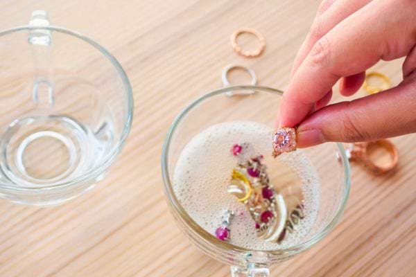 Bijoux trempant dans un verre d’eau savonneuse pour être nettoyés.