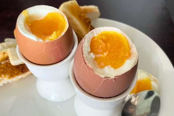 Deux œufs à la coque ouverts dans des coquetiers.