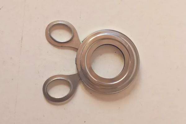 Petit objet rond en métal avec deux anneaux.
