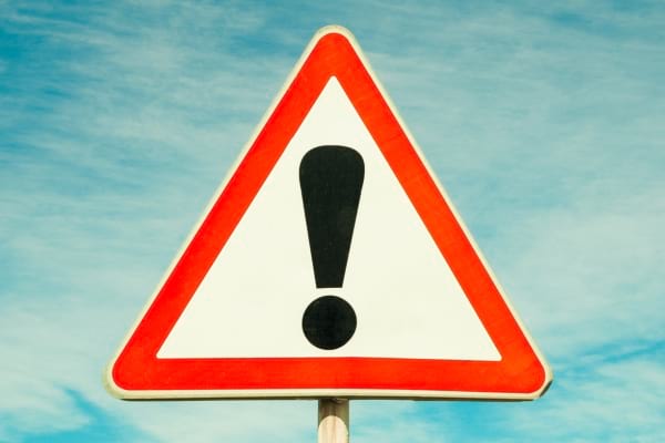 Panneau triangulaire rouge avec point d’exclamation noir.