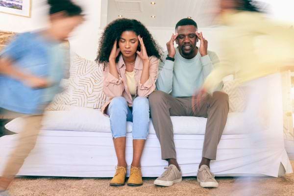 Parents assis fatigués pendant que des enfants courent autour d’eux.