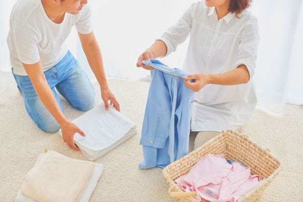 Un couple plie et range le linge ensemble à la maison.