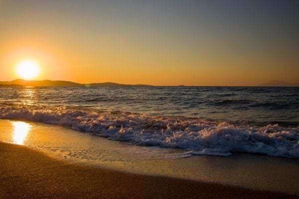 Plage au coucher de soleil avec vagues.