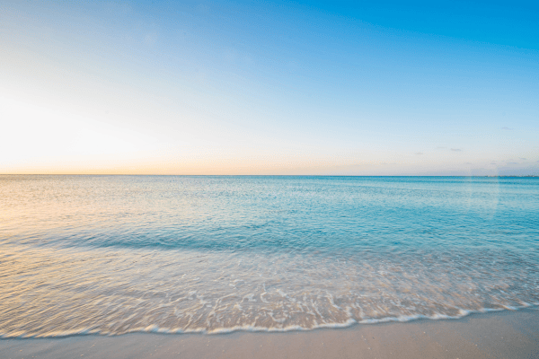 Une plage paisible au lever du soleil avec une eau calme et limpide.